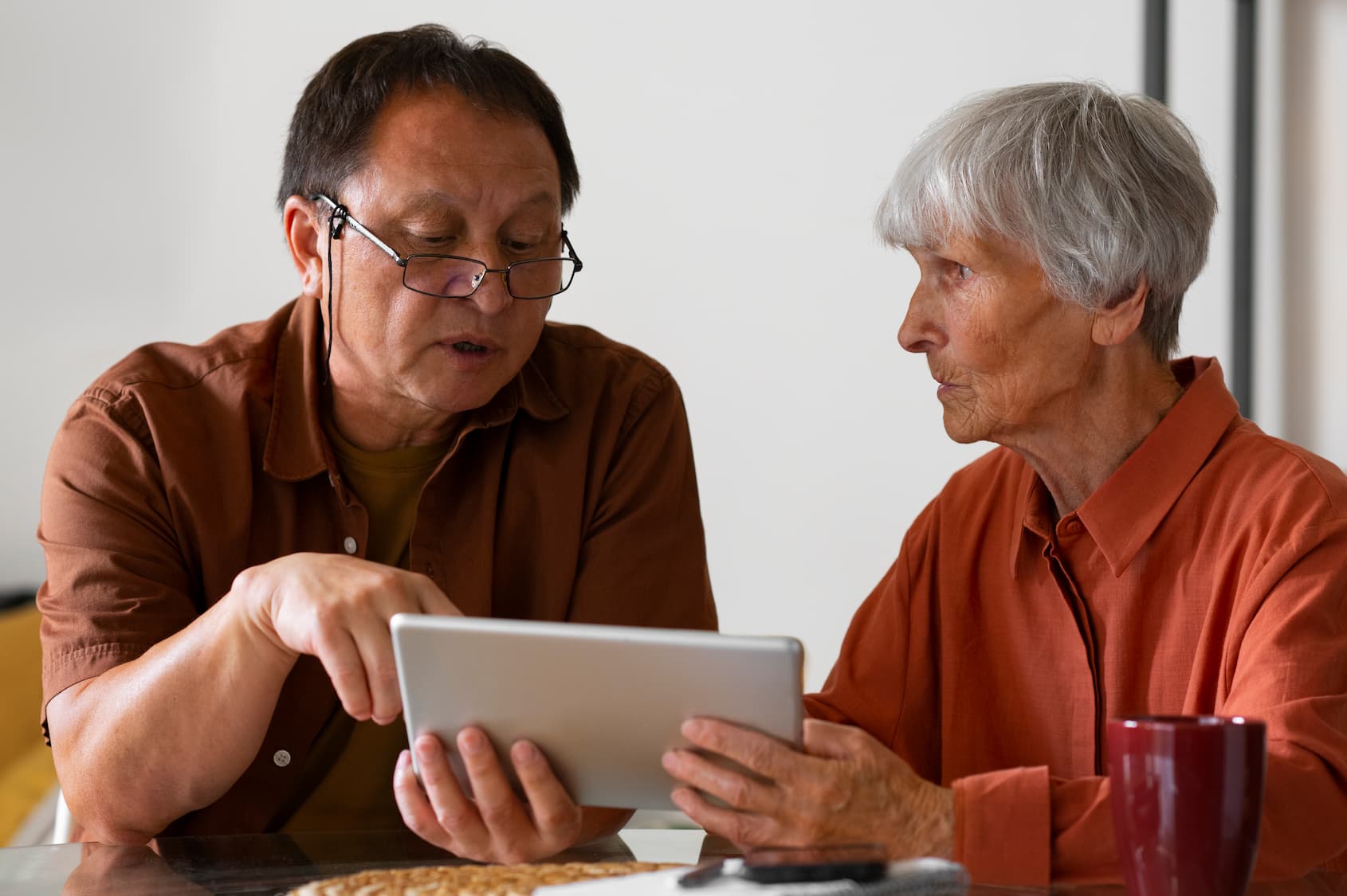 Elderly man teaching elderly woman how to use tech devices